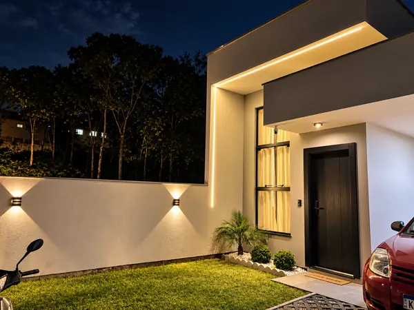 Fachada à noite com arandelas e perfil de LED instalados