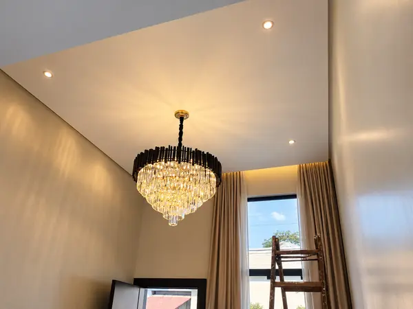 Lustre de cristal instalado em sala de pé-direito alto